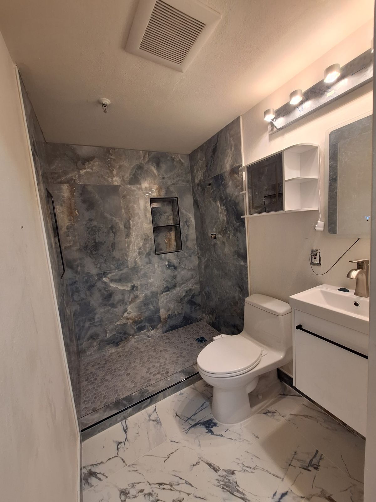 Walk-in shower in large-format tile with a hex mosaic floor