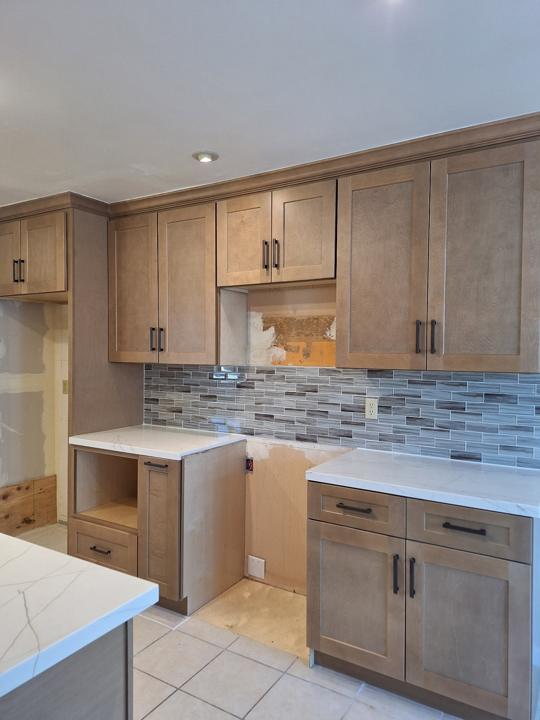 Stained shaker cabinets, quartz counters and glass tile backsplash, mid-install
